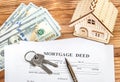 Mortgage deed with keys, money and model of house on the table