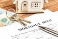 Mortgage deed with keys, money and model of house on the table Royalty Free Stock Photo