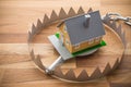 Mortgage house in a trap on wooden table background. House trap on debt or loan problem or risk in real estate property financing Royalty Free Stock Photo