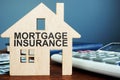 Mortgage insurance. Wooden home, money and calculator