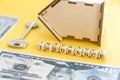 mortgage, insurance, loan and home purchase. Model of house, dollar bills, key on white and yellow isolated background. Free space Royalty Free Stock Photo