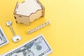 mortgage, loan and home purchase. Model of house, dollar bills, key on white and yellow isolated background. Free space for text, Royalty Free Stock Photo