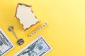 mortgage, loan and home purchase. Model of house, dollar bills, key on white and yellow isolated background. Free space for text, Royalty Free Stock Photo