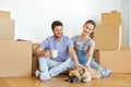 Happy couple with boxes and dog moving to new home Royalty Free Stock Photo