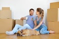 Happy couple with boxes and dog moving to new home Royalty Free Stock Photo