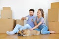 Happy couple with boxes and dog moving to new home Royalty Free Stock Photo