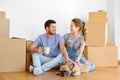 Happy couple with boxes and dog moving to new home Royalty Free Stock Photo