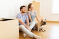 Happy couple with boxes and dog moving to new home Royalty Free Stock Photo