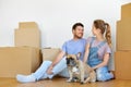 Happy couple with boxes and dog moving to new home Royalty Free Stock Photo