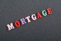 MORTGAGE word on black board background composed from colorful abc alphabet block wooden letters, copy space for ad text. Learning Royalty Free Stock Photo