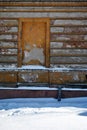 Mortgaged window of the old brick building with cracked plaster, winter snowy street