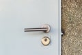 Mortise lock with a knob and keyhole on a metal door painted in gray. Closed entrance from the street to the utility room. Locked