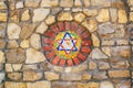 Mosaic star of David on stone wall.