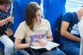 MOSCOW, AUG.29, 2018: View on the girl reading a book and other seating people in passenger train saloon on new Moscow Ring Railwa