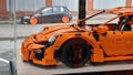 Moscow. Autumn 2018. The original Lego Porsche 911 Gt3 RS at the Porsche dealership. Low real car with orange wheels on background