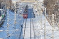 MOSCOW, FEB. 01, 2018: Winter sunny day view on red passenger train coming to railway station people on platform, man on rail trac