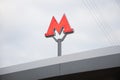 Moscow metro logo on the roof of the station. Shot from the lower angle. Red letter M on a background of a cloudy sky