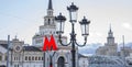Moscow metro sign and Stalinist architecture on background. Selective focus on Metro sign