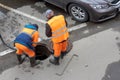 Workers over the open sewer hatch on a street