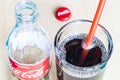 Drink in glass with straw and bottle of Coca-Cola