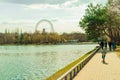 Moscow, Russia April 18 2021: girl riding scooter on pond edge at Izmailovsky park, big ferris wheel Royalty Free Stock Photo