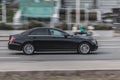 Side view of black Mercedes E-class car riding on the road on high speed. Shiny black sedan car in motion. Urban scene with riding Royalty Free Stock Photo
