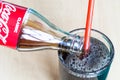 Pouring of Coca-Cola drink from bottle into glass Royalty Free Stock Photo