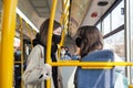 Two cheerful girls in protective masks in a city bus