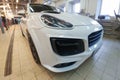 Moscow, Russia - April 19, 2019: White Porsche Cayenne in TechArt Magnum wide body kit. Stands in service center. Front and side