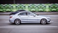 A woman drives Mercedes C-Class at high speed. A silver sedan car drives fast through the city with motion blur effect. Excess Royalty Free Stock Photo