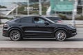 Young girl uses a mobile phone in the car. Black Porsche Cayenne car moving on the street. Compliance with speed limits on road Royalty Free Stock Photo