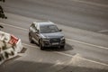 Black car Audi Q7 is driving off motorway on street. Aerial front side view of premium SUV auto