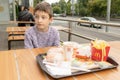 MOSCOW, RUSSIA - AUGUST 02, 2019: A boy sitting on summer terrace by the table in Macdonalds fast food restaurant - burgers,