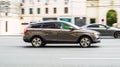 Brown Lada Vesta SW Cross compact station wagon driving on high speed in city street