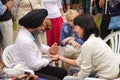 An elderly bearded Indian in a black turban gives a woman an acupressure of the hand