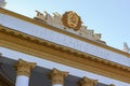 Moscow, Russia - August 01, 2018: Gilded coat of arms of RSFSR over colonnade of pavilion RSFSR on VDNH in Moscow on a blue sky