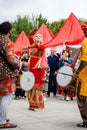 indian drummer playing traditional dhol instrument and russian woman dancing in the street. Fest day of india in Moscow