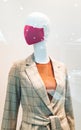 Moscow, Russia - August 15, 2020: red masked mannequin wearing women`s brown checked jacket in mall showcase