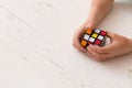 Moscow, Russia, August 24, 2017: Rubik`s cube in the hands of a child, closeup, top view, white wooden background