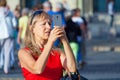 Senior woman takes a pictures on the phone on a background of a crowd of tourists
