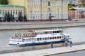 Small cruise ship with passengers sails on the Moscow river on a background of Sofiyskaya embankment