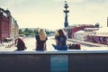 Two young girls sitting on a bridge over the Moscow river with a view to Peter the Great, Krasny Oktyabr and Muzeon park