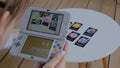 Woman gamer using game console Nintendo 3ds with AR app