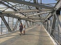 Woman with girl on a scooter crossing an overhead pedestrian bridge in Moscow