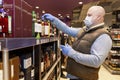 Moscow, Russia, 09/04/2020: A bald adult man in a medical mask and gloves chooses alcohol in a supermarket. Depression in self-