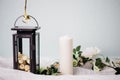 Moscow, Russia - 06 10 2018: black metal lamp with white roses, candle and flowers on light background, home decor, Royalty Free Stock Photo