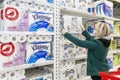 Moscow, Russia, 03/26/2020: A blond woman in a medical mask buys a lot of toilet paper in a supermarket. Panic and deficiency