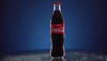 Moscow, Russia - 14 04 2020: Bottle glass of classic Coca-Cola rotate on mirrored table blue background. Nice footage of