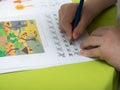 A boy does his homework. Distance learning in quarantine. Textbooks, notebooks are on the table. child`s hand with a pencil Royalty Free Stock Photo