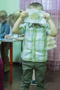 A boy holding his ready picture behind face.